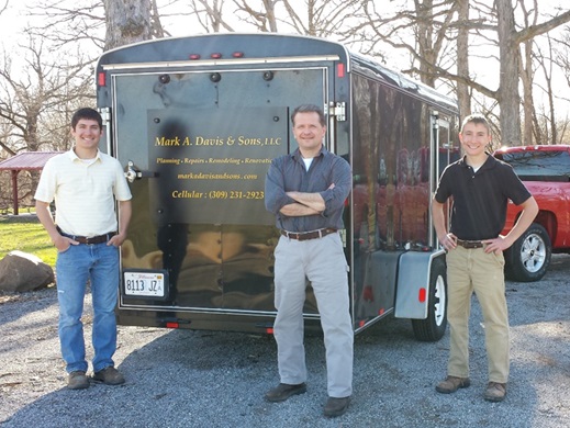 Mark Davis and his sons standing by work trailer